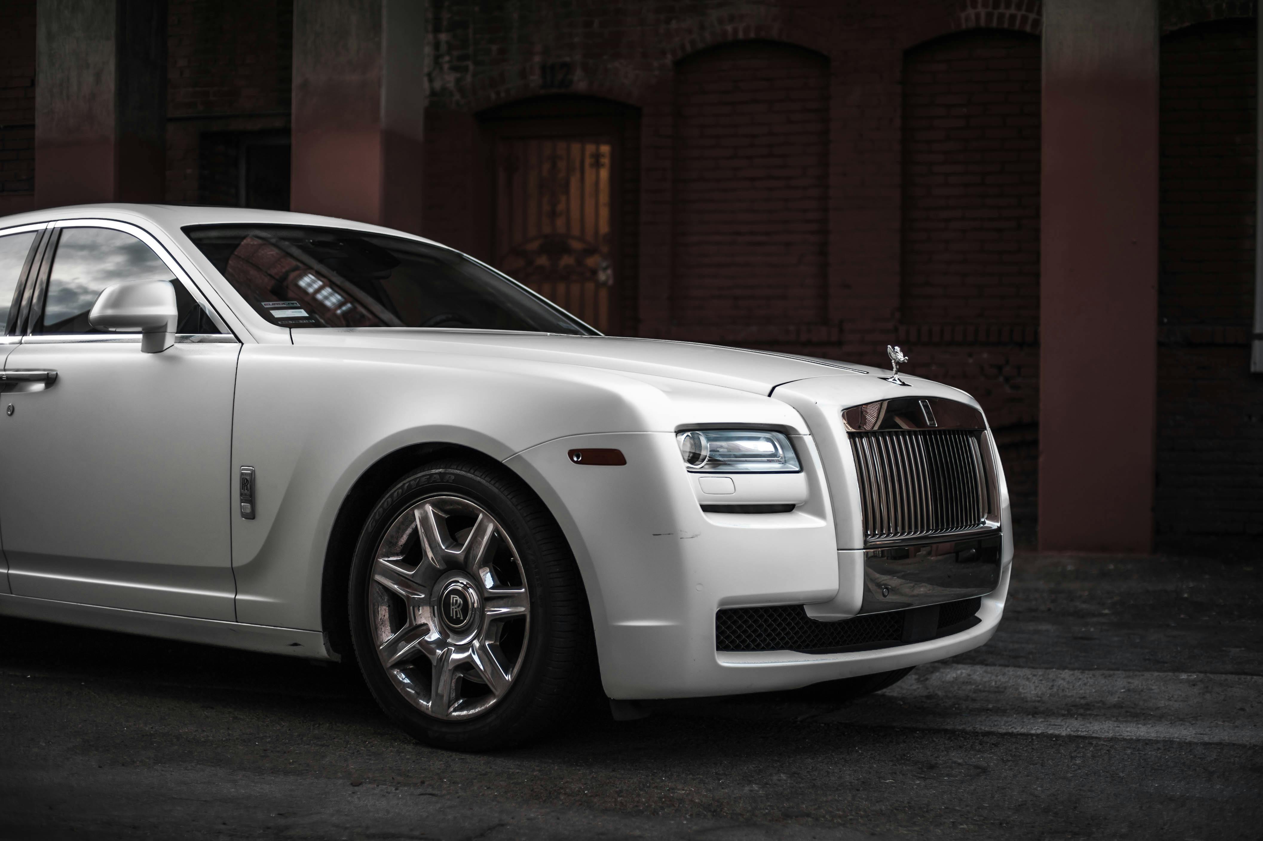 Elegant white Rolls Royce Ghost parked in a stylish urban backdrop, showcasing luxury and design.